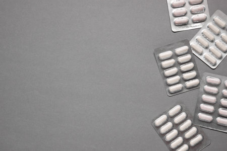Different antibiotic pills in blisters on gray background, flat lay. Space for textの写真素材