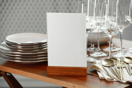 Menu holder, clean dishware and cutlery on wooden table indoors