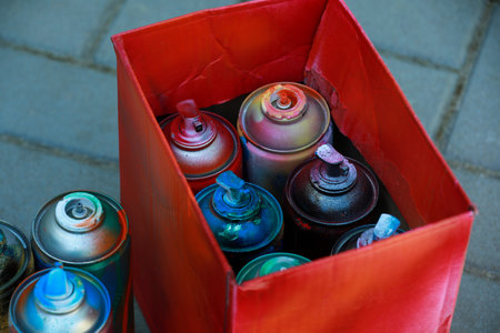 Many spray paint cans and red cardboard box outdoors, closeupの写真素材