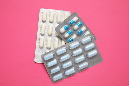 Different antibiotic pills in blisters on pink background, top viewの写真素材