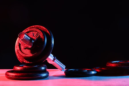 Parts of barbell on table in color lights. Space for textの写真素材
