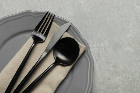 Stylish cutlery, napkin and plate on gray table, top view. Space for textの写真素材