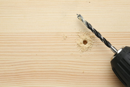 Cordless electric drill on holed wooden surface, top view. Space for textの写真素材