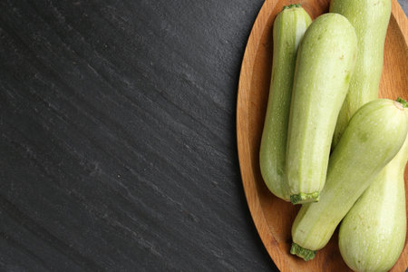 Fresh zucchinis on dark textured table, top view. Space for textの写真素材
