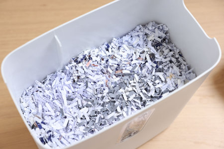 Shredded paper strips in bin on wooden table, closeupの写真素材