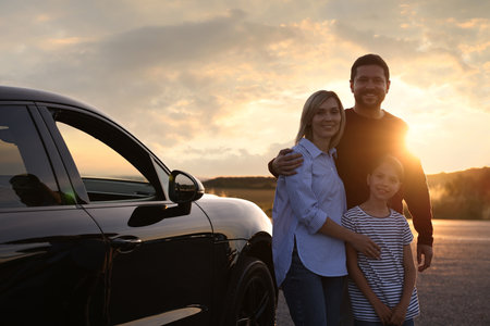 Cute family near car outdoors at sunsetの写真素材