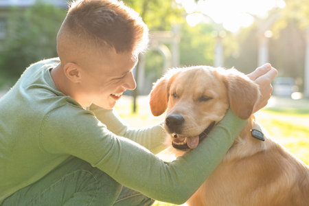 Young man with his lovely dog in park on sunny dayの写真素材