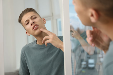Man touching his face near mirror indoorsの写真素材