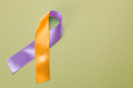 World Psoriasis Day. Orange and orchid awareness ribbon as symbol of support on olive color background, top view. Space for textの写真素材