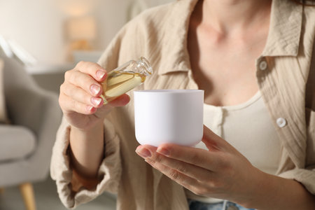 Woman adding essential oil to aroma diffuser at home, closeupの写真素材