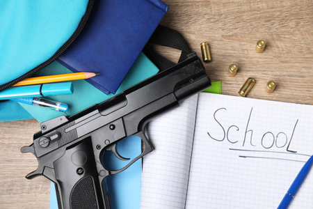 Gun, bullets and school stationery on wooden table, flat layの写真素材
