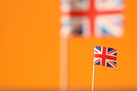 Small paper flags of United Kingdom on orange background, selective focus. Space for textの写真素材