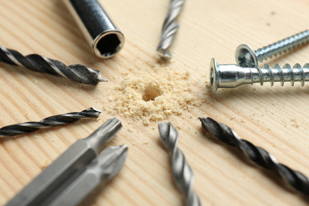 Different drill bits on holed wooden surface, closeupの写真素材