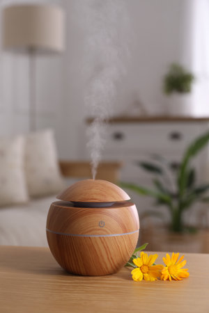 Essential oil diffuser and calendula flowers on wooden table at home