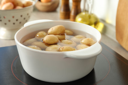 Boiling potatoes in pot on stove in kitchenの写真素材