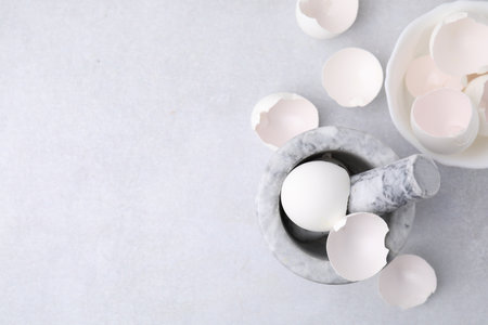 Broken eggshells, mortar and pestle on gray table, flat lay. Space for textの写真素材