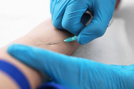 Nurse inserting IV into arm of patient in hospital, closeup