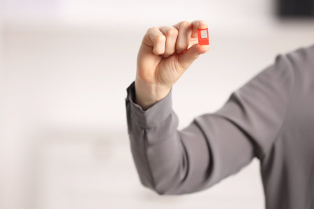 Woman holding SIM card indoors, closeup. Space for textの写真素材