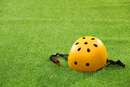 Yellow protective helmet on green grass, space for textの写真素材