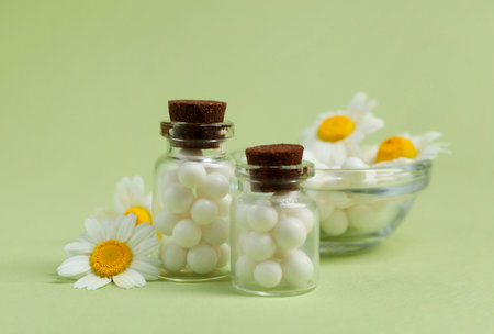 Homeopathic remedy and chamomiles on light green background, closeupの写真素材