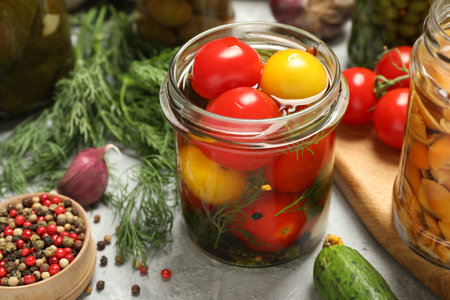 Tasty pickled tomatoes in jar and fresh ingredients on gray table, closeupの写真素材