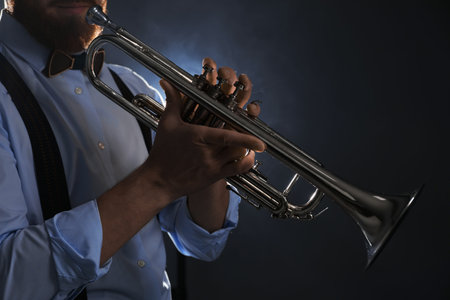 Professional musician holding trumpet on dark background, closeupの写真素材