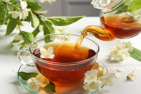 Pouring hot jasmine tea into cup on white marble table, closeupの写真素材