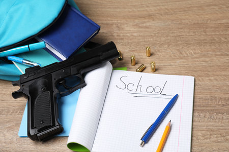 Gun, bullets and school stationery on wooden table, above viewの写真素材