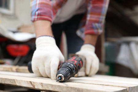 Man working with electric screwdriver outdoors, closeupの写真素材