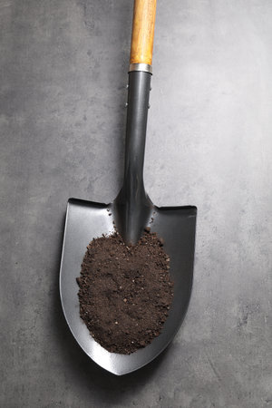 Metal shovel with soil on gray table, top viewの写真素材