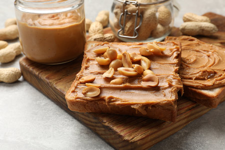 Tasty sandwiches with peanut butter and nuts on gray textured table, closeup