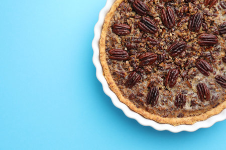 Delicious pecan pie in baking dish on light blue background, top view. Space for textの写真素材