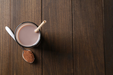 Delicious protein shake in glass and spoon with powder on wooden table, top view. Space for textの写真素材