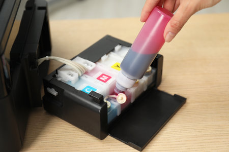 Woman refilling ink in modern printer at workplace indoors, closeup