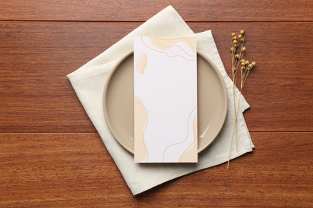 Empty menu, plate, napkin and dry flowers on wooden table, top view. Mockup for designの写真素材