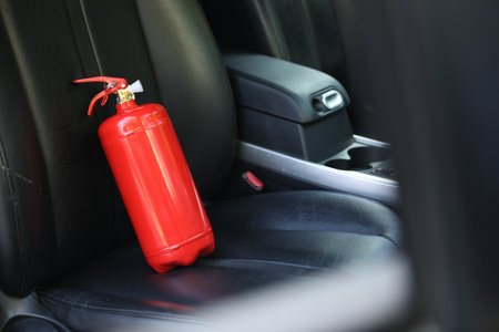 Red fire extinguisher in automobile. Car safety equipment