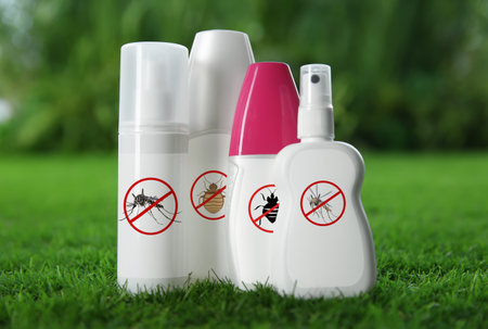 Different insect repellents in spray bottles on green grass outdoorsの写真素材