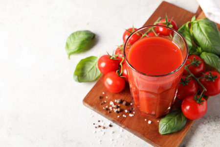 Tasty tomato juice in glass, spices and fresh vegetables on light table, space for textの写真素材