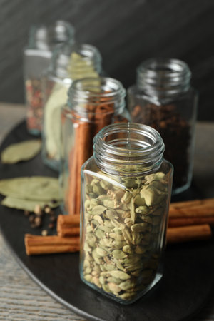 Different spices in glass jars on gray wooden table, closeupの写真素材