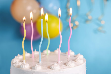 Tasty Birthday cake with burning candles against light blue background, closeupの写真素材