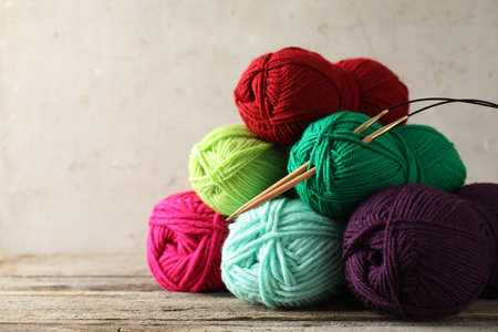 Pile of different yarns and knitting needles on wooden table, closeup. Space for textの写真素材