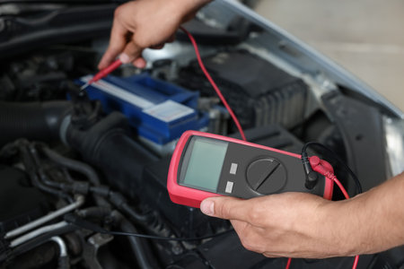 Auto mechanic with multimeter doing diagnostic at automobile repair shop, closeupの写真素材