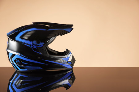 Modern motorcycle helmet with visor on mirror surface against beige background. Space for textの写真素材