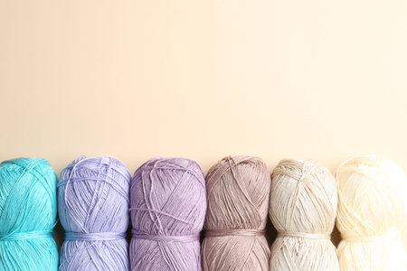 Different colorful yarns on beige background, flat lay. Space for text