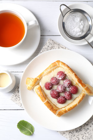 Tasty puff pastry with raspberries and tea on white wooden table, flat layの写真素材