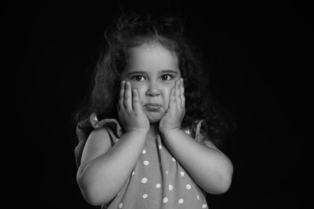 Portrait of emotional girl on dark background. Black and white effect