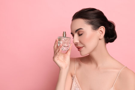 Beautiful woman with bottle of perfume on pink background. Space for textの写真素材