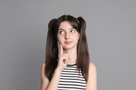 Portrait of cute teenage girl on grey backgroundの写真素材