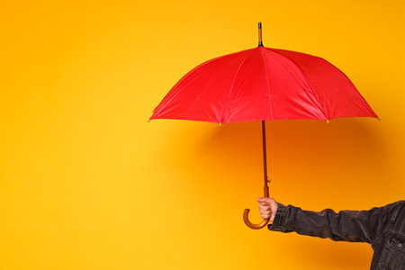 Man holding red umbrella on yellow background, closeup. Space for textの写真素材