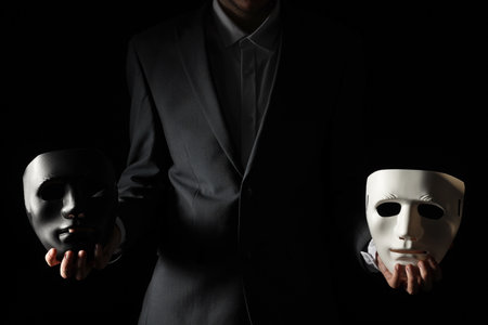 Theatrical performance. Man holding plastic masks on black background, closeupの写真素材